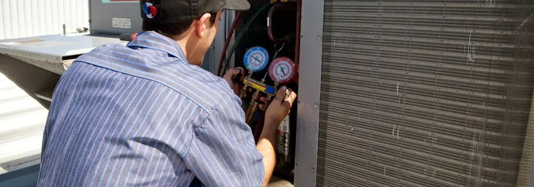 HVAC technician servicing a condenser unit in Port St. Lucie